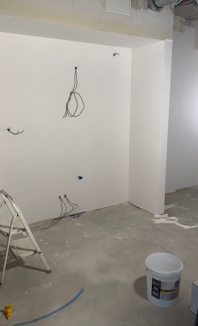 Das Foto zeigt eine weiße Wand in der neuen Filiale Büderich. Kabel von Lampen hängen an der Wand herunter.