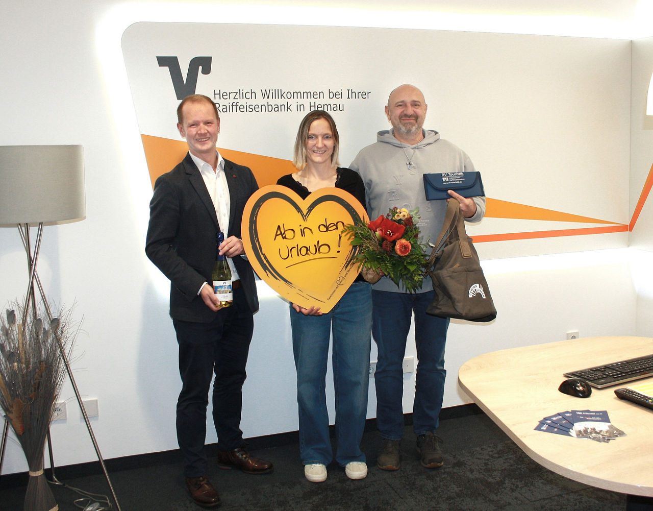 Gewinner halten ihren Gewinn, Blumen und ein Gewinnsparherz in der Filiale Hemau