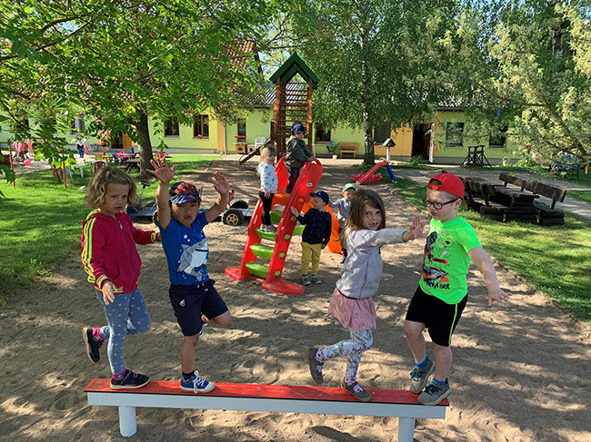 Kinder spielen auf einem Spielplatz, gehen auf einer roten Bank