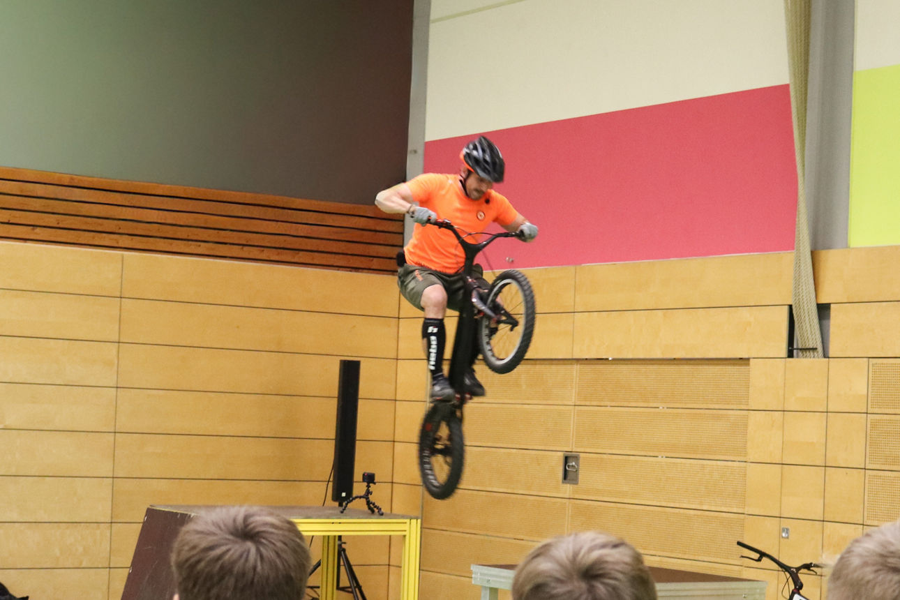 Junger Mann mit Helm springt mit seinem Fahrrad über ein Hindernis
