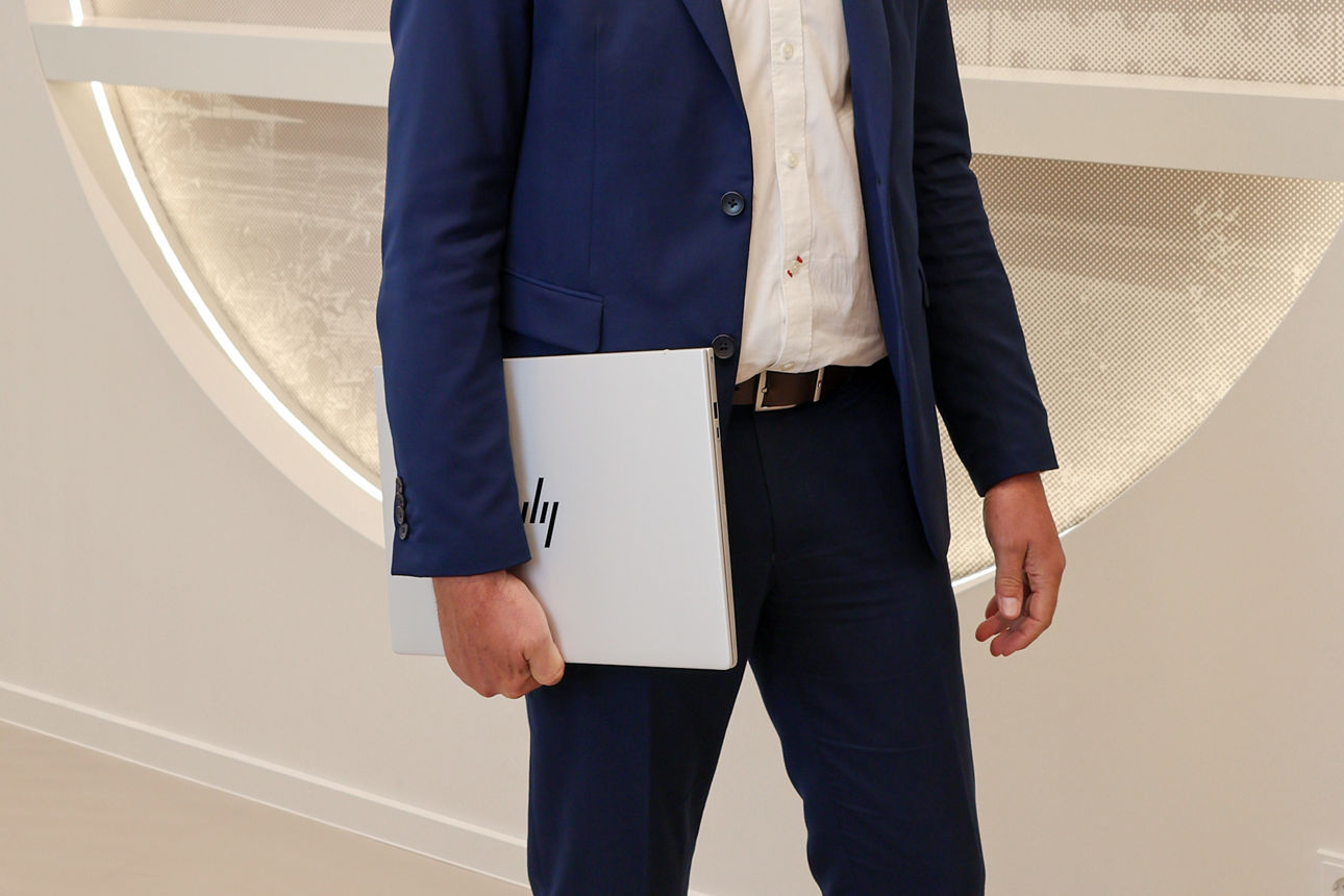 Ein Mann hält einen geschlossenen Laptop in seiner Hand