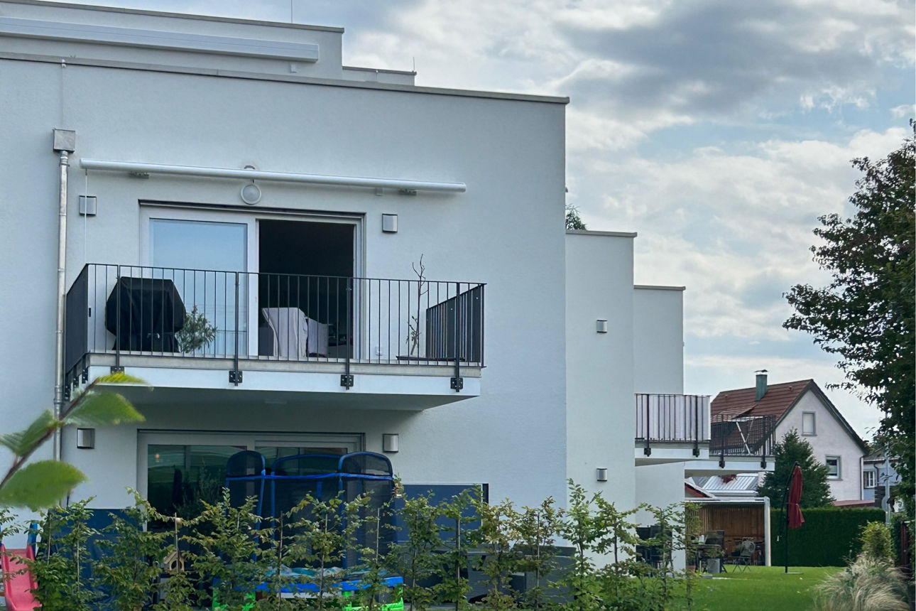 Garten eines Neubau Mehrfamilienhauses mit Blick auf einen Balkon.