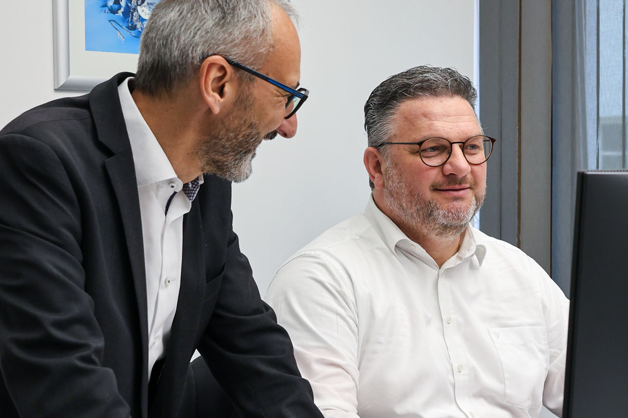 Zwei Männer sind gemeinsam am Schreibtisch 