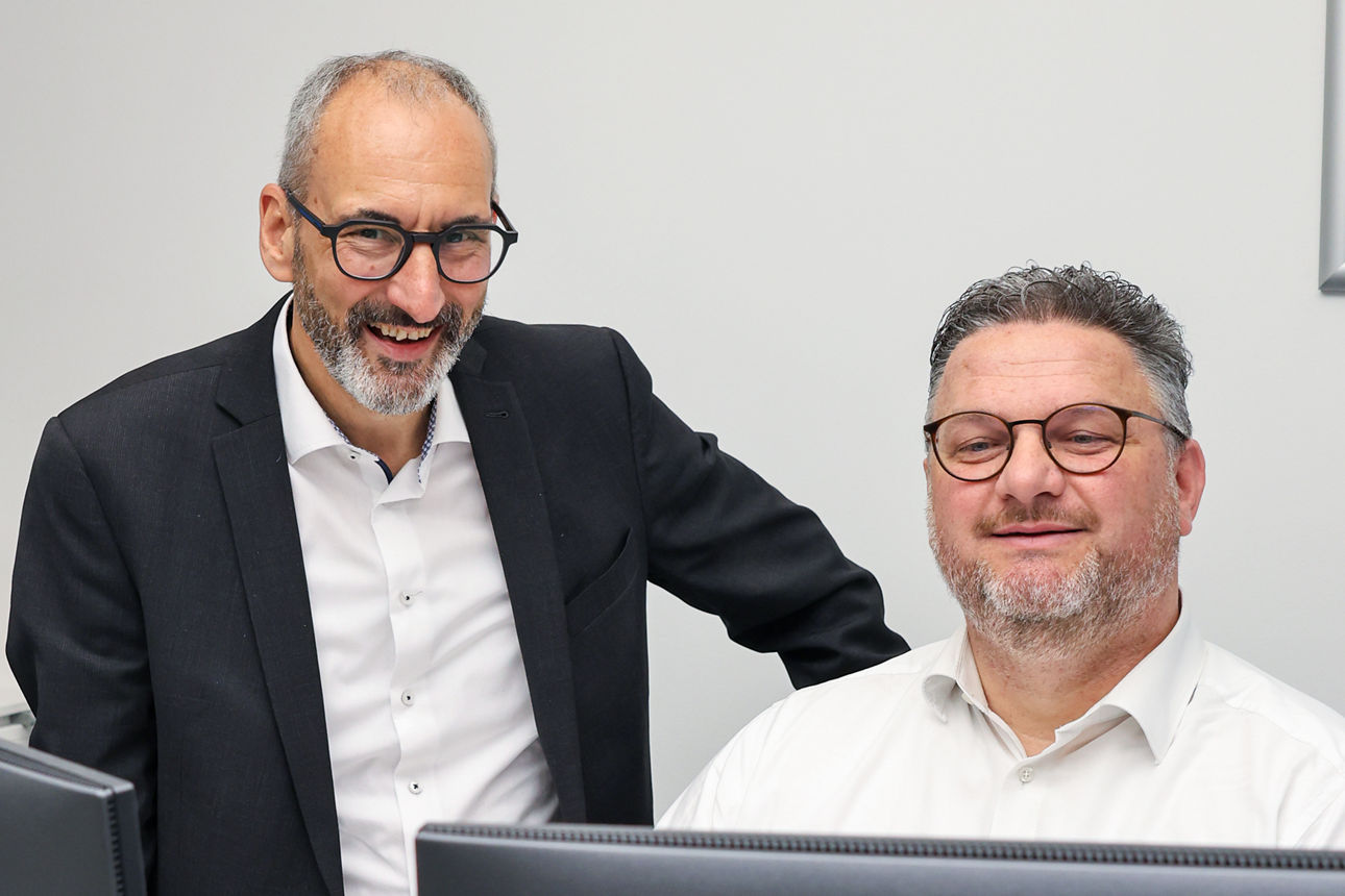 Lächelnde Männer, die in einen PC schauen