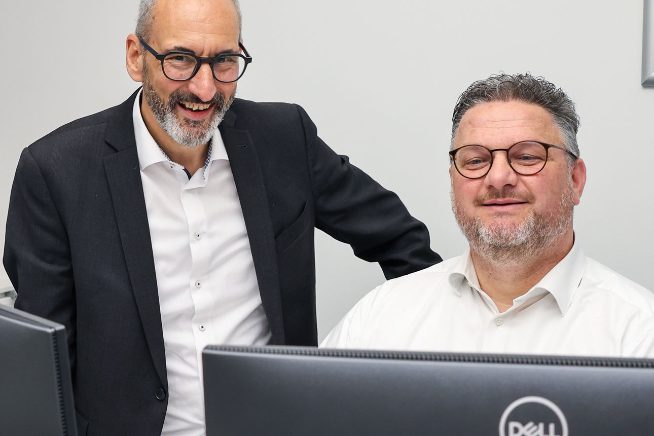 Zwei Männer schauen gemeinsam in den PC