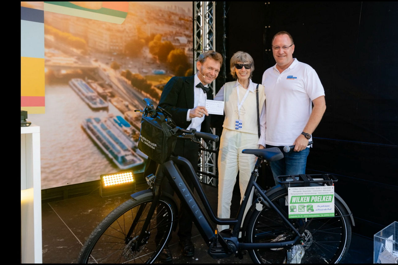 Gewinnerin des E-Bike mit Vorstand und Moderator auf der Bühne