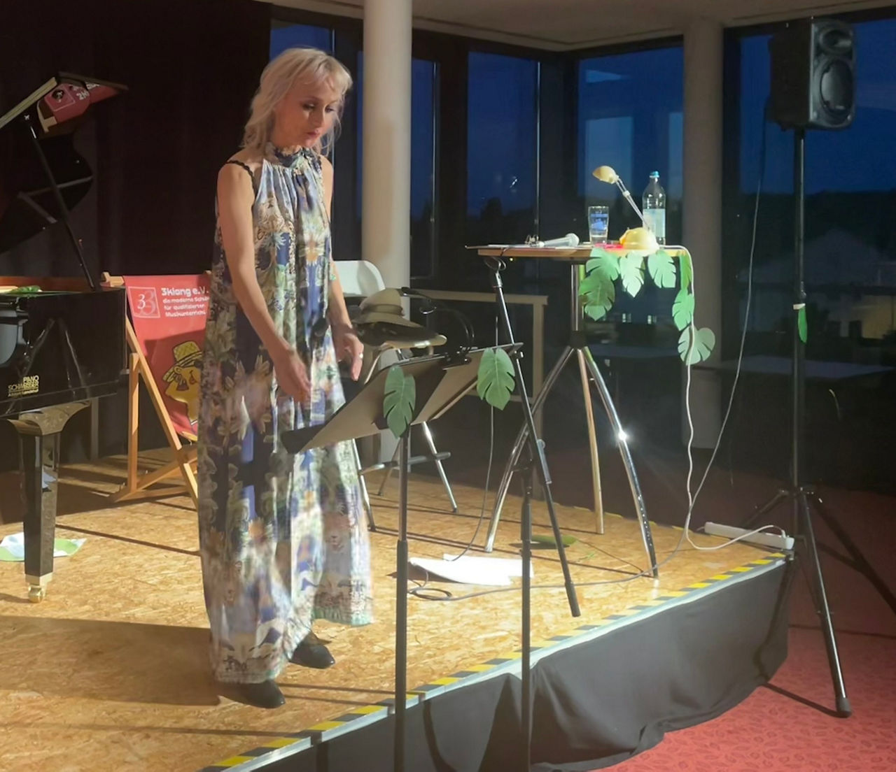 Die Musikkünstlerin Tanja Maria Foidl steht auf der dekorierten Bühne der Freisinger Bank während des Mark-Twain-Konzerts