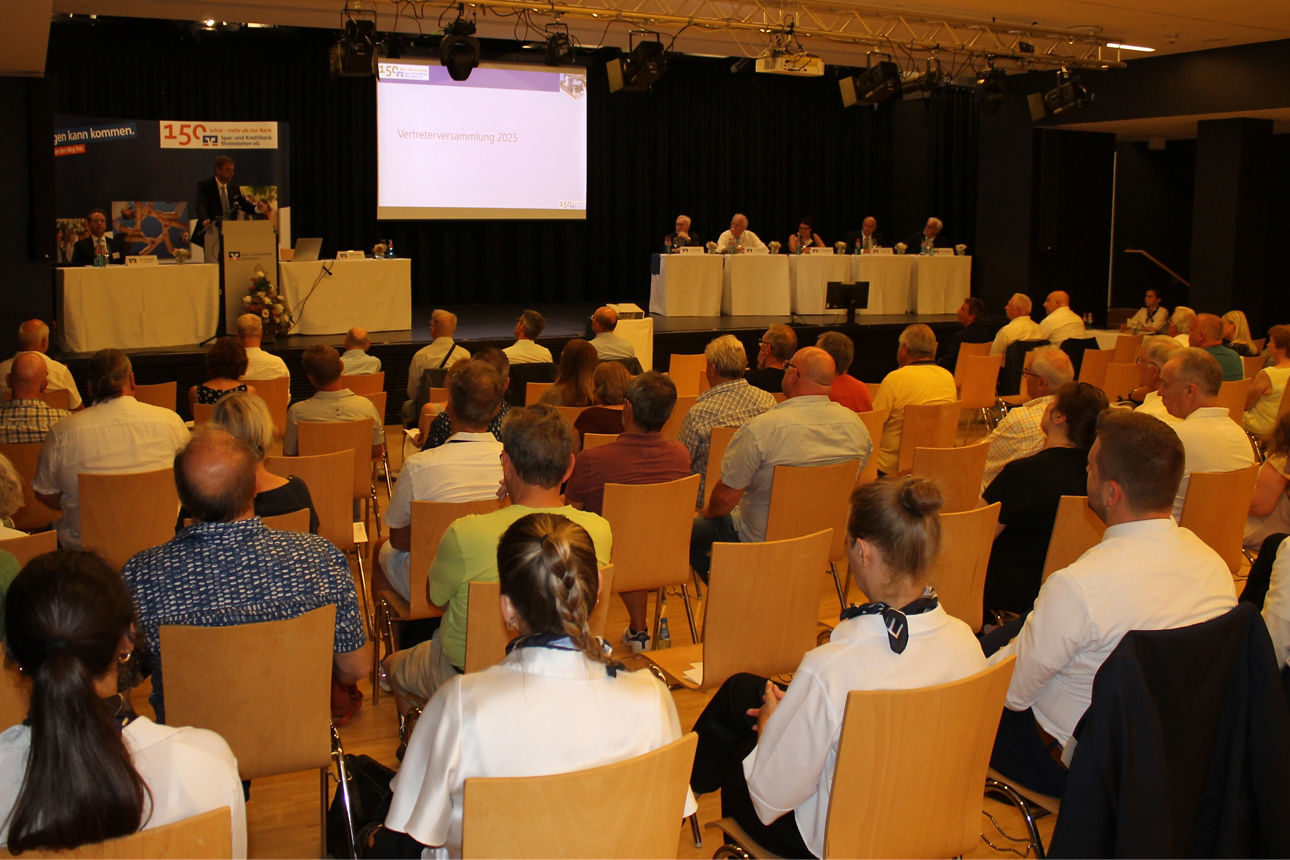 Sitzreihen mit Personen die auf die Bühne schauen.