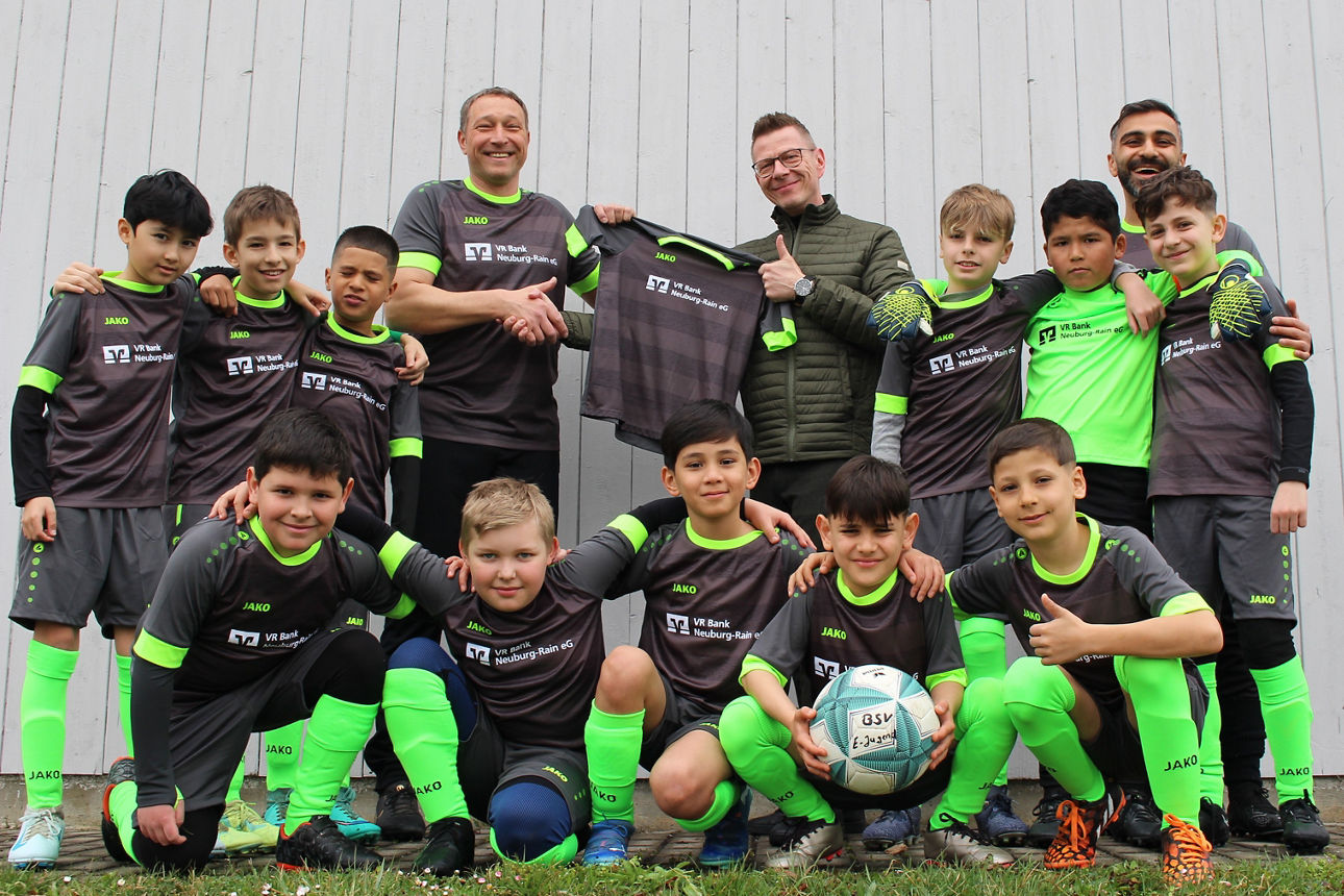 Eine junge Fußballmannschaft posiert gemeinsam mit den Trainern in den neuen Trikots.