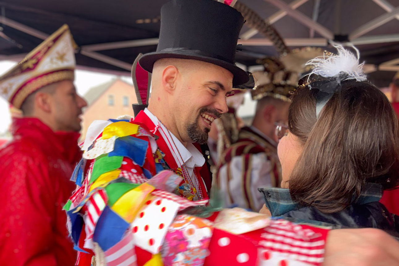 Stephanie Kröll überreicht Adjutant Christian, der einen Zylinder mit Hasenohren trägt, einen Orden und umarmt ihn
