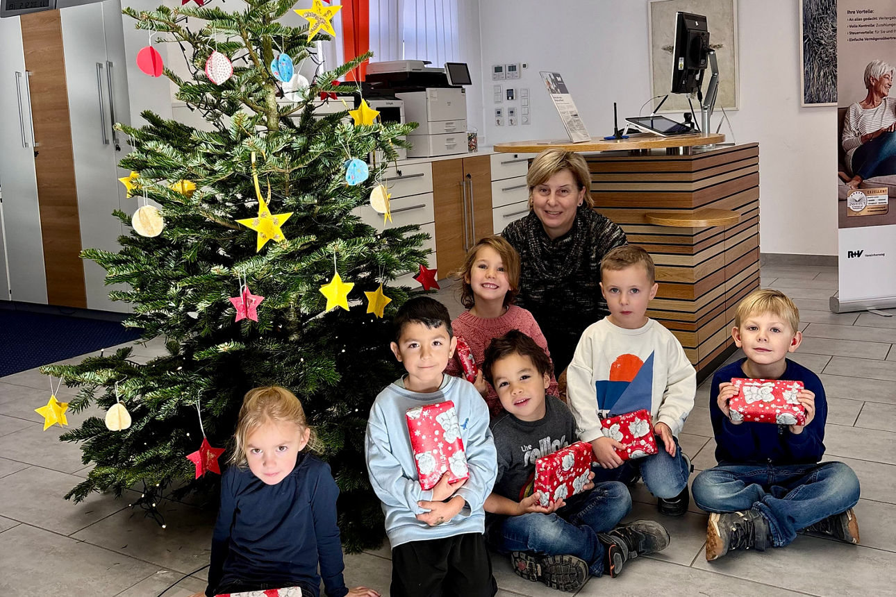 Kinder in der Bankfiliale mit Geschenken und einem Weihnachtsbaum. 