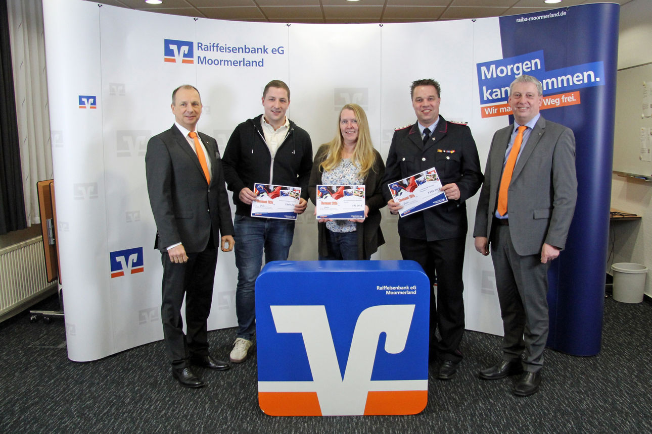 Vereinsmitglieder stehen mit Scheck vor der Werbewand