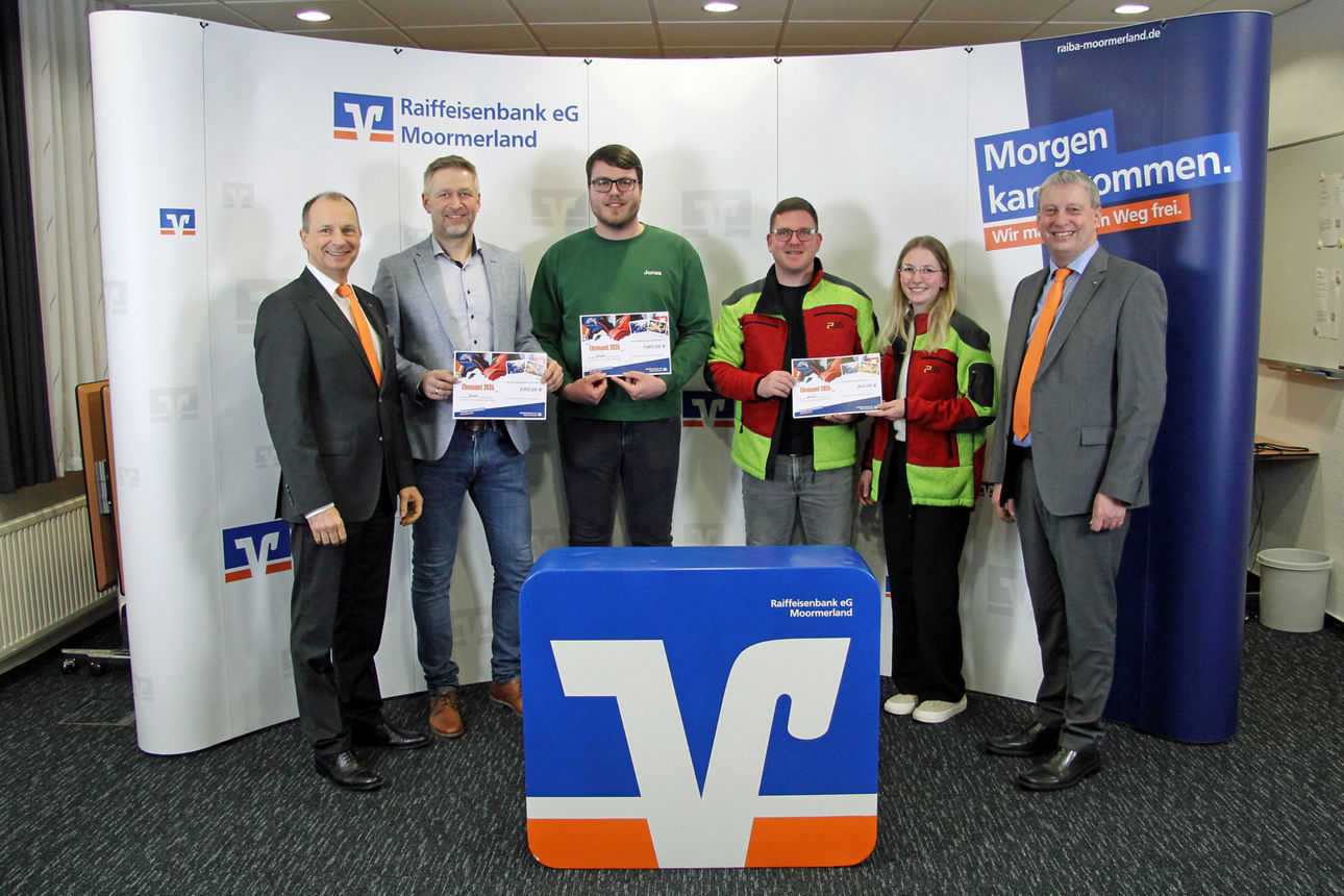 Vereinsmitglieder stehen mit Scheck vor der Werbewand