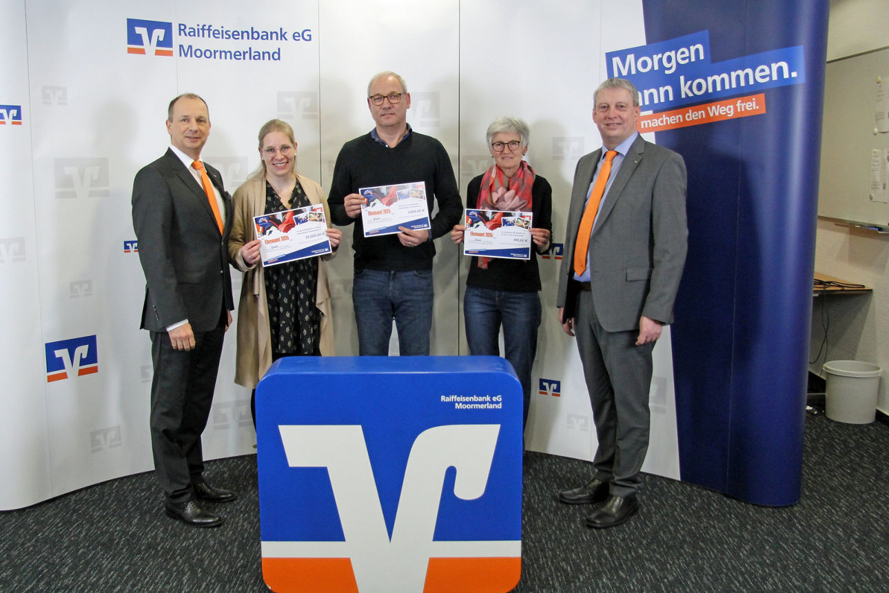 Vereinsmitglieder stehen mit Scheck vor der Werbewand