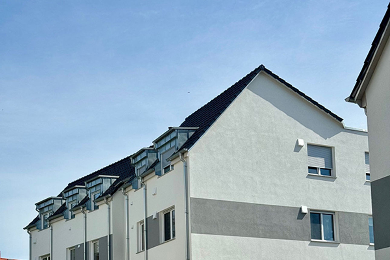 Vollständiger Wohnblock mit Dach von der Seite gesehen und mit sichtbaren Parkplätzen