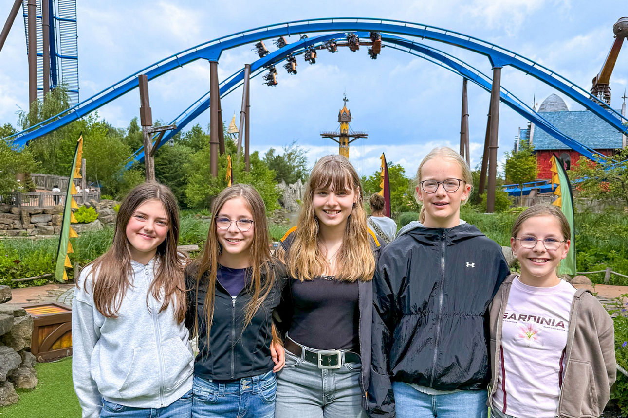 fünf Jugendliche posieren vor einem Fahrgeschäft 