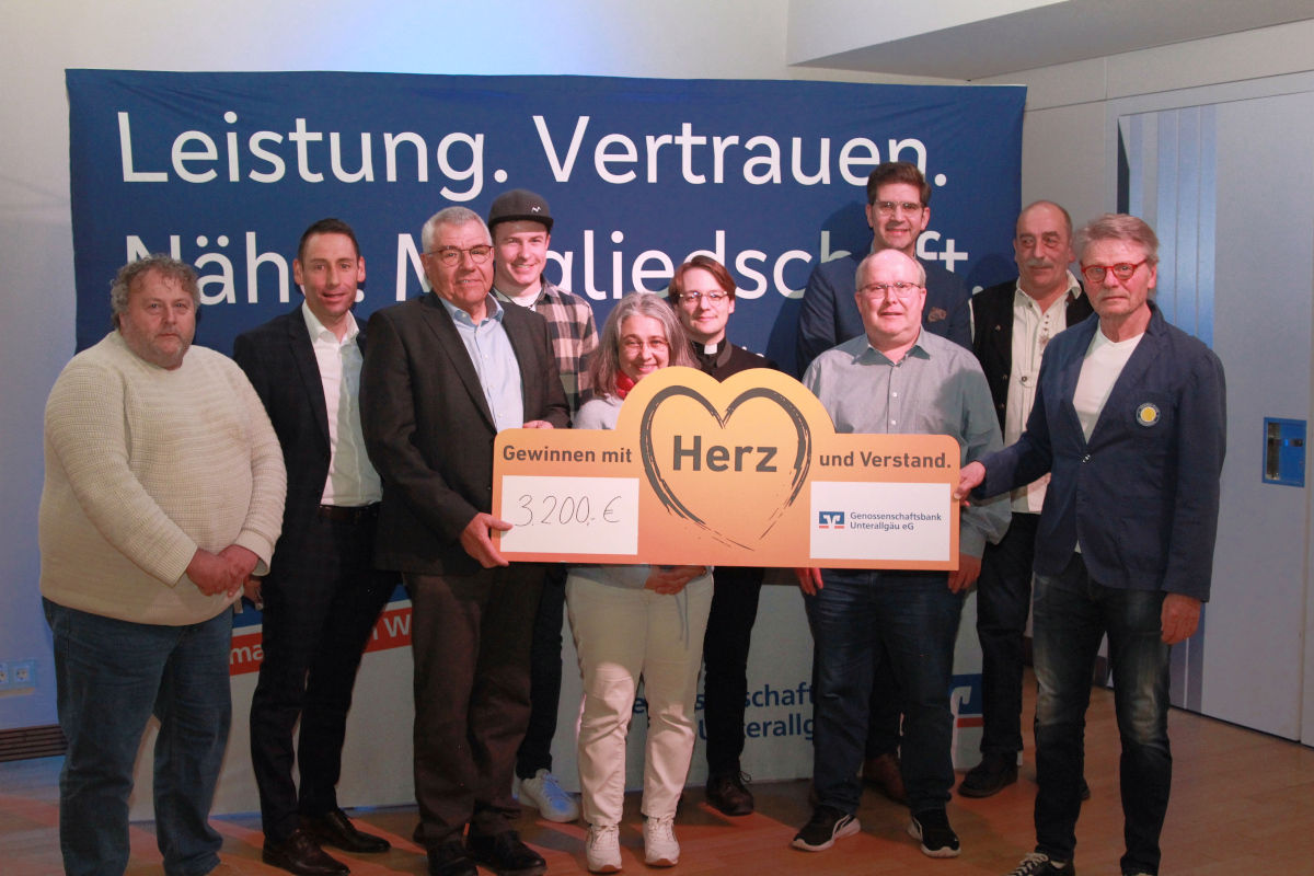 Mitgliedes des Vereins stehen mit großem Spendenscheck vor einer Leinwand