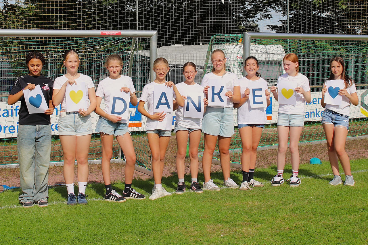 Vereinsmitglieder halten den Schriftzug "Danke" auf einem Fußballplatz in die Höhe
