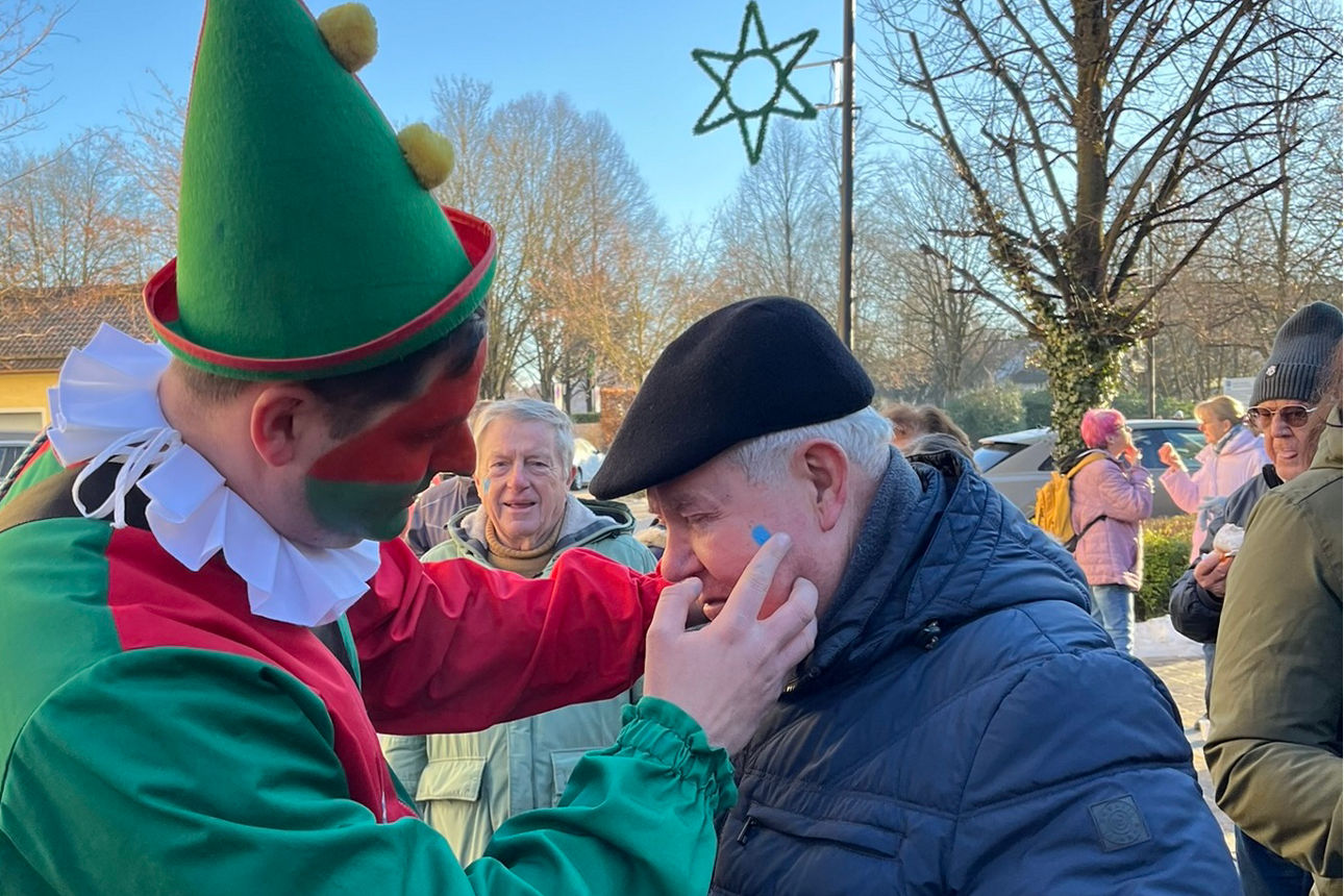 Kasperl malt Herz auf die Wange eines Besuchers