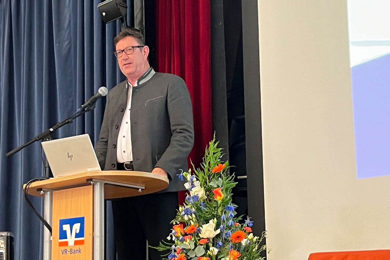 Mann steht vor Rednerpult und spricht zum Publikum.