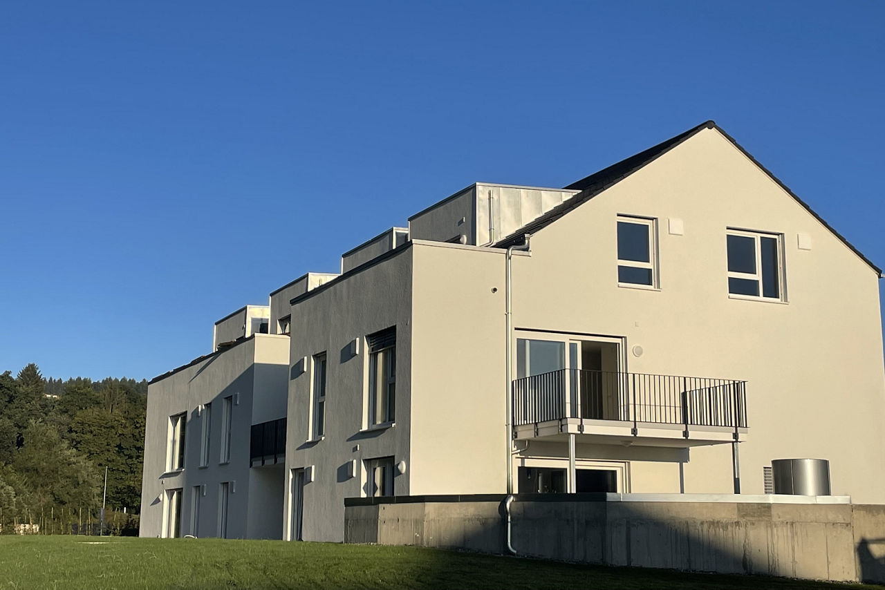 Modell eines Neubau Mehrfamilienhauses mit Spitzdach und Balkonen. Rechts die Aufschrift "Wohnen in Aitrach".