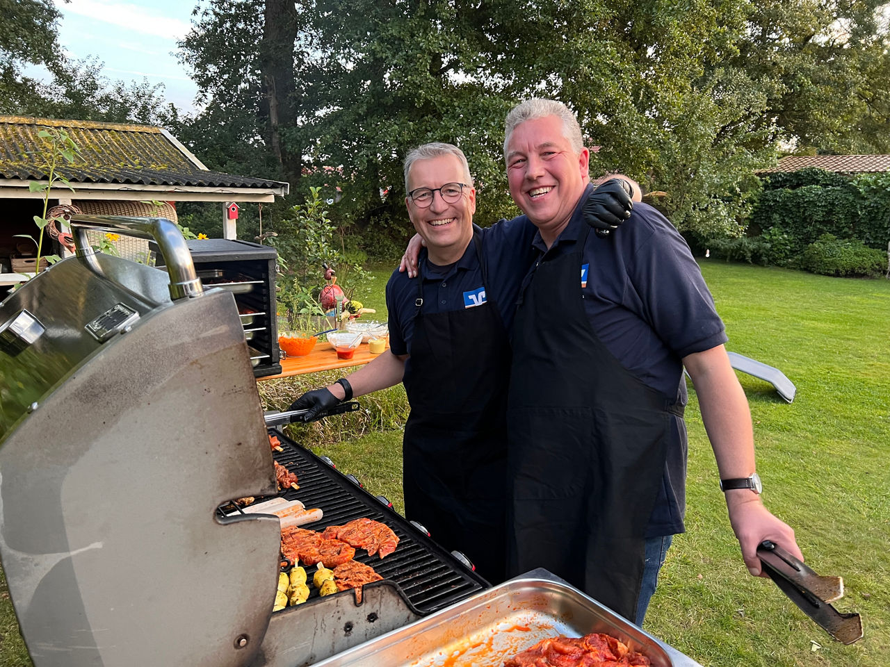 Zwei Mitarbeiter grillen in einem Garten