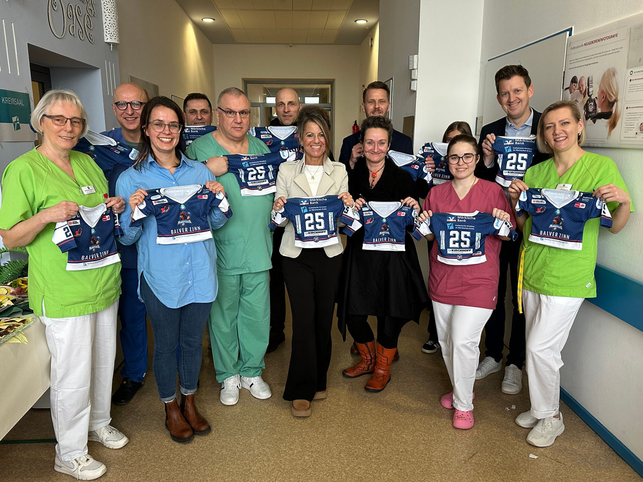 Gruppenfoto: Mitarbeiter des Bethanien Krankenhaus und der Filialleiter aus Iserlohn halten die neuen Mini-Trikots hoch