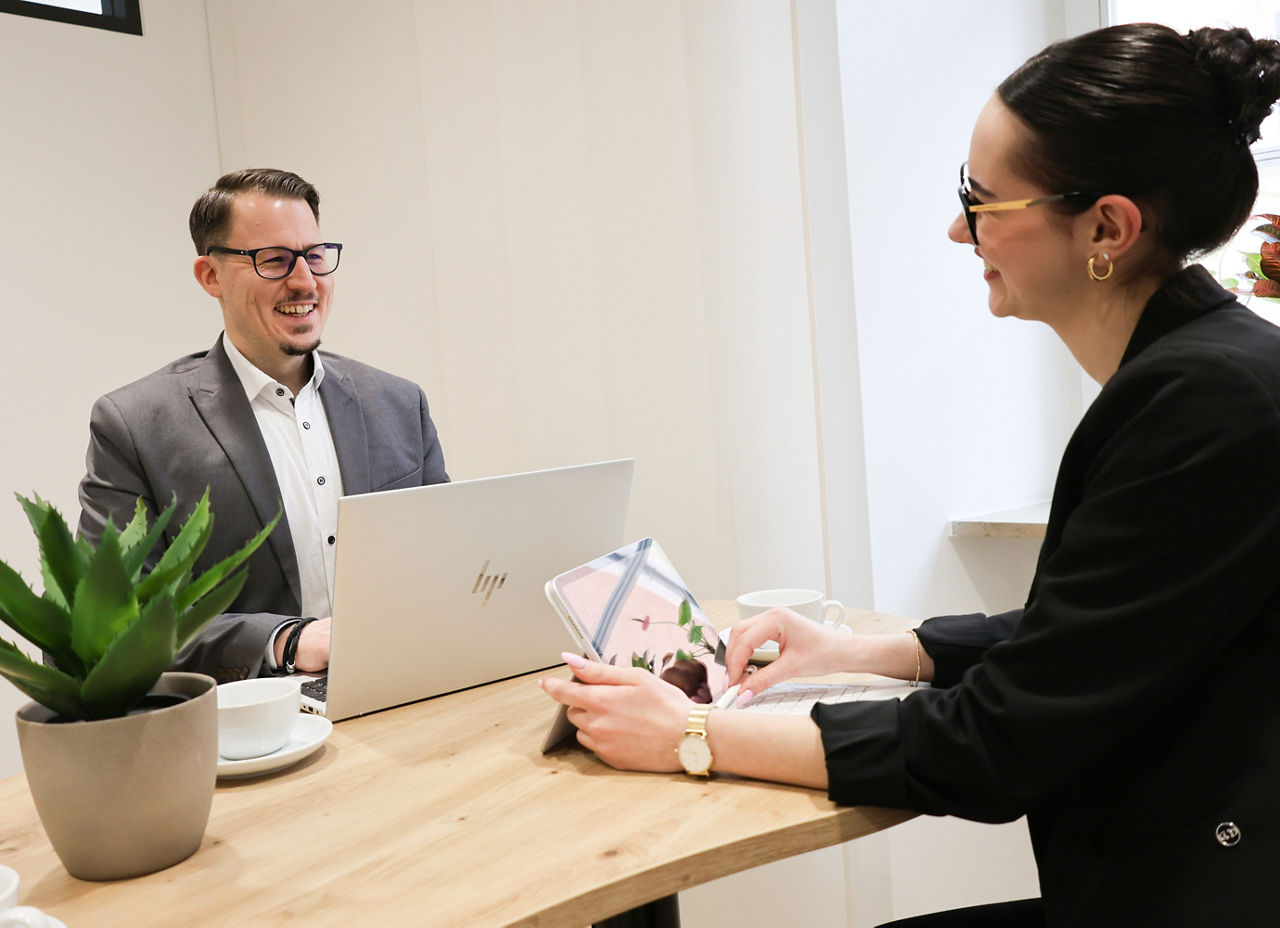 Zwei Personen sitzen mit Laptops am Schreibtisch
