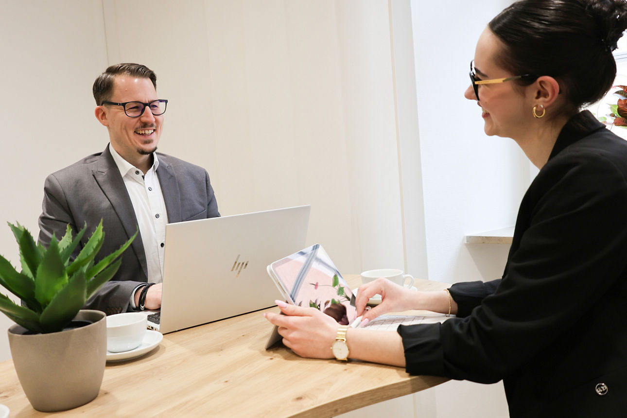 Zwei Personen sitzen mit Laptops am Schreibtisch