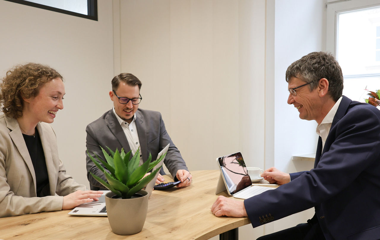 Eine Frau und zwei Herren arbeiten gemeinsam an einem Projekt