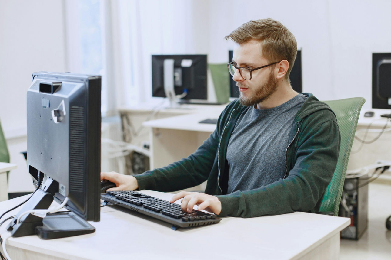 Ein Mann sitzt an einem Schreibtisch und schaut vertieft in seinen Monitor