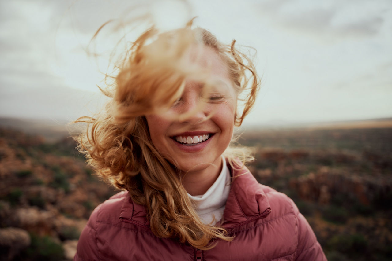 Eine Frau steht im Wind und die Haare fallen in ihr Gesicht