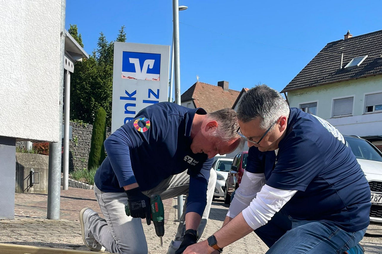 Zwei Männer bauen ein Holzgerüst zusammen