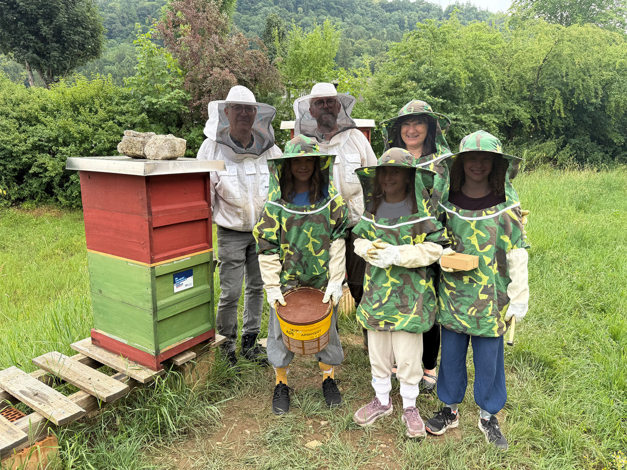 Gruppe der Imker AG der Realschule Stühlingen in Imkerschutzkleidung neben einem Bienenstock.