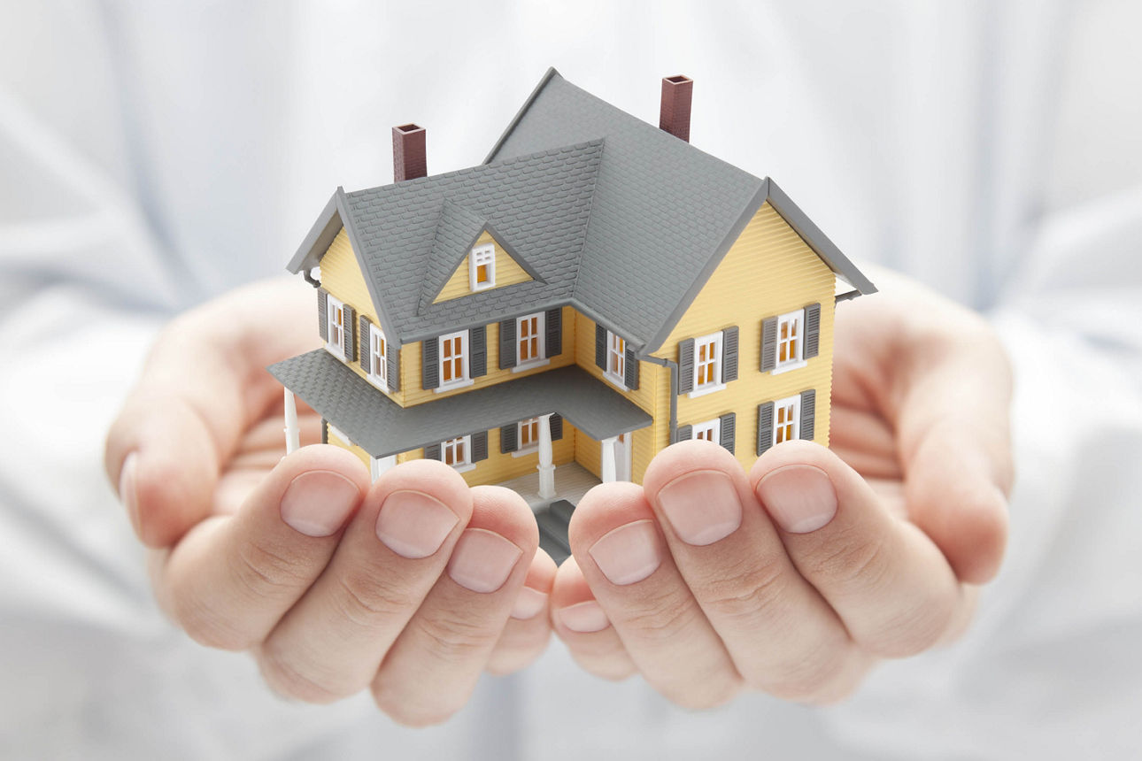 Ein kleines zweistöckiges Haus wird in zwei Händen gehalten
