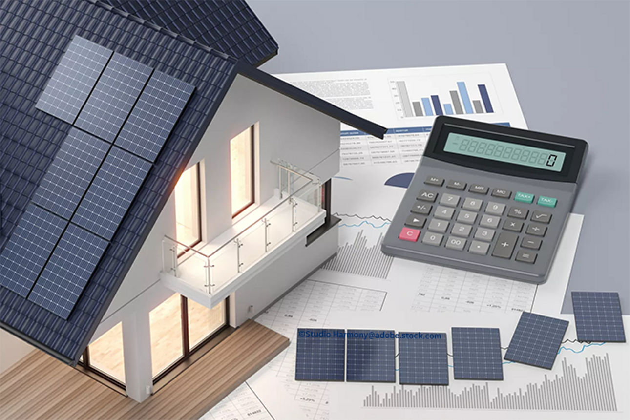 Miniaturhaus mit einem Taschenrechner und Papieren daneben