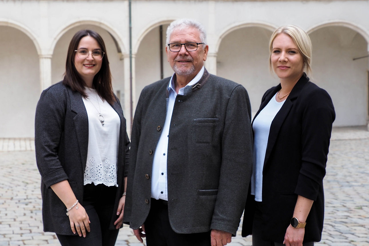 zwei Frauen und ein Mann vor einem historischen Gebäude