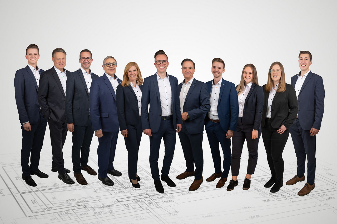 Mitarbeitende der Volksbank Allgäu-Oberschwaben eG in Corporate Fashion, stehend vor einem neutralen Hintergrund.