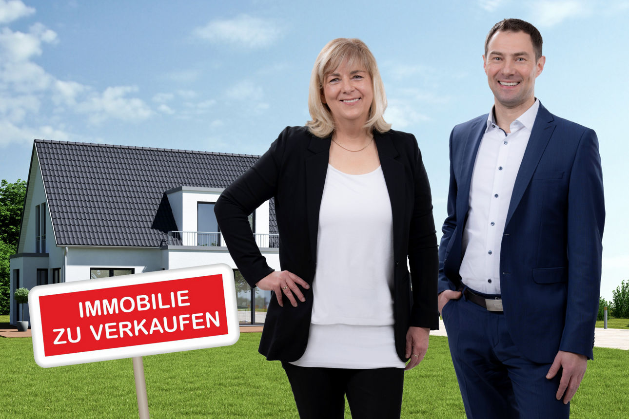 Immobilienvermittler Ilka Hüttner und Ronny Schramm vor einem Einfamilienhaus auf grüner Wiese