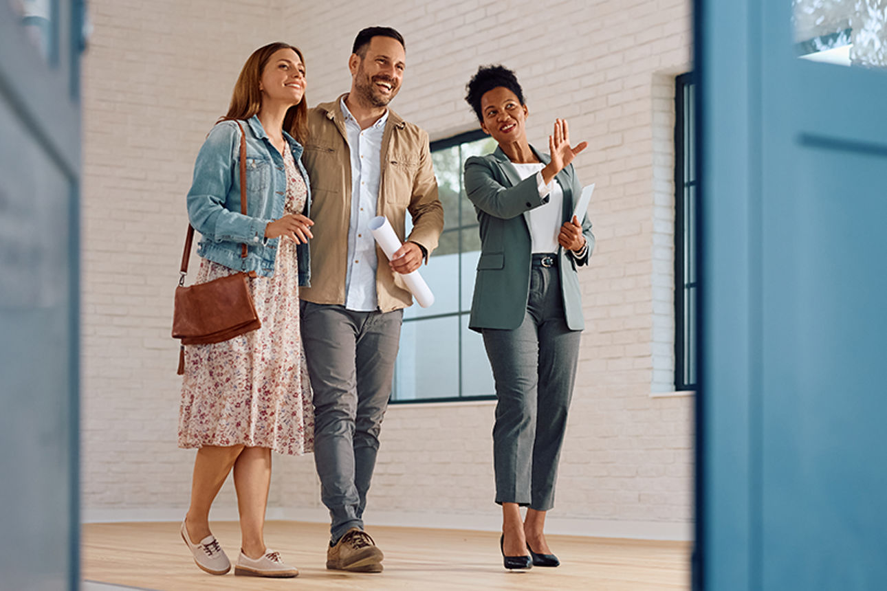 Familie (Mann und Frau) die ein Haus von einer Maklerin gezeigt bekommen