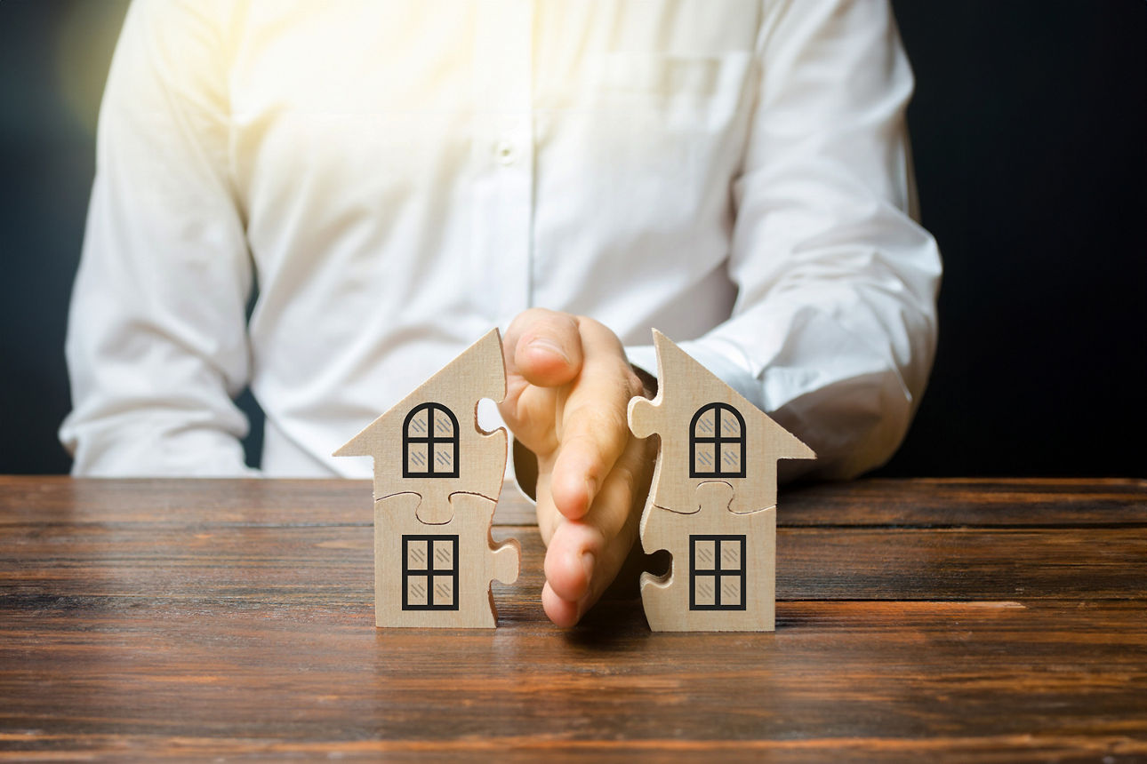 Eine Hand teilt das Modell eines Hauses