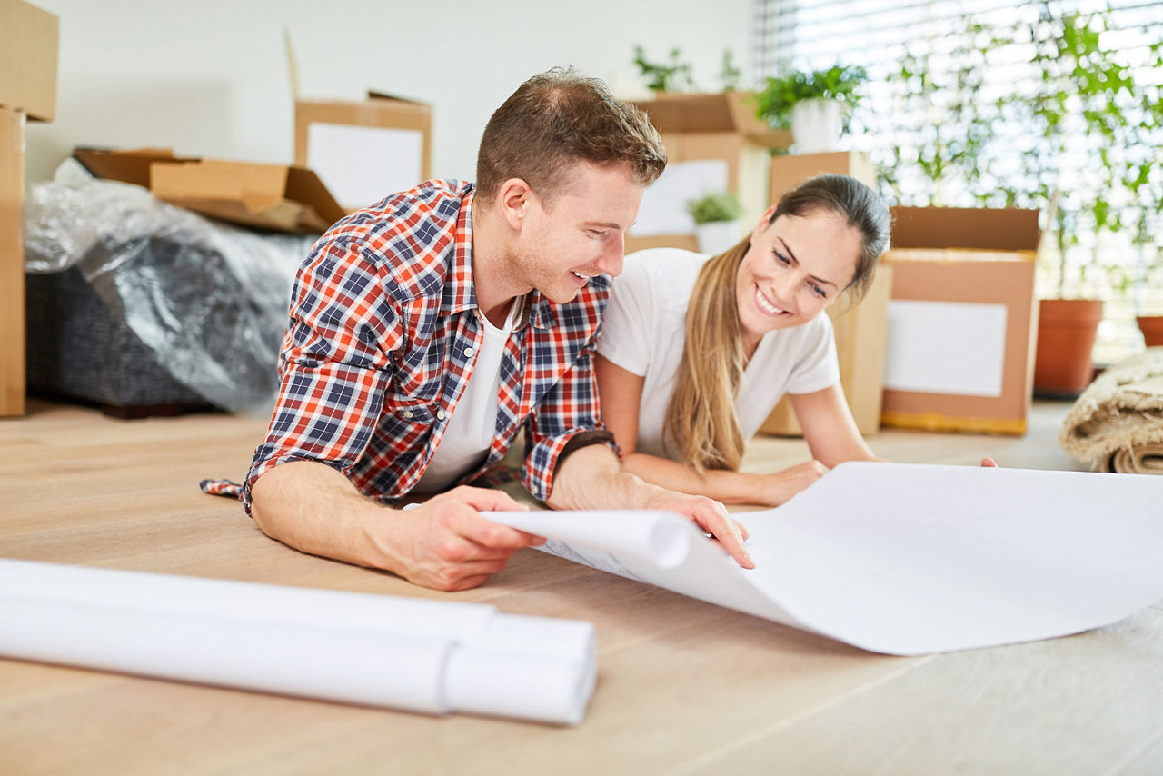 Glückliches junges Paar bei der Planung von Hausbau oder Hauskauf mit Bauplan