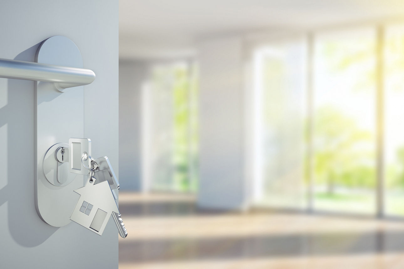 Schlüssel im Türschloss vor leerem sonnigem Appartment