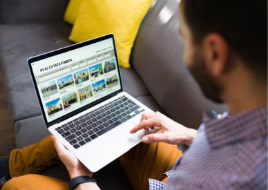 Mann schaut auf einen Laptop mit Immobilienangeboten