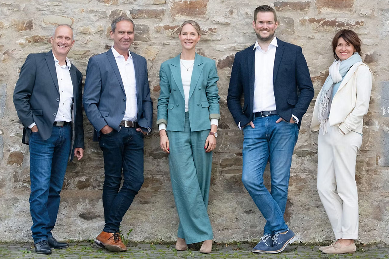 Unsere Immobilienberater stehen vor einer Hauswand