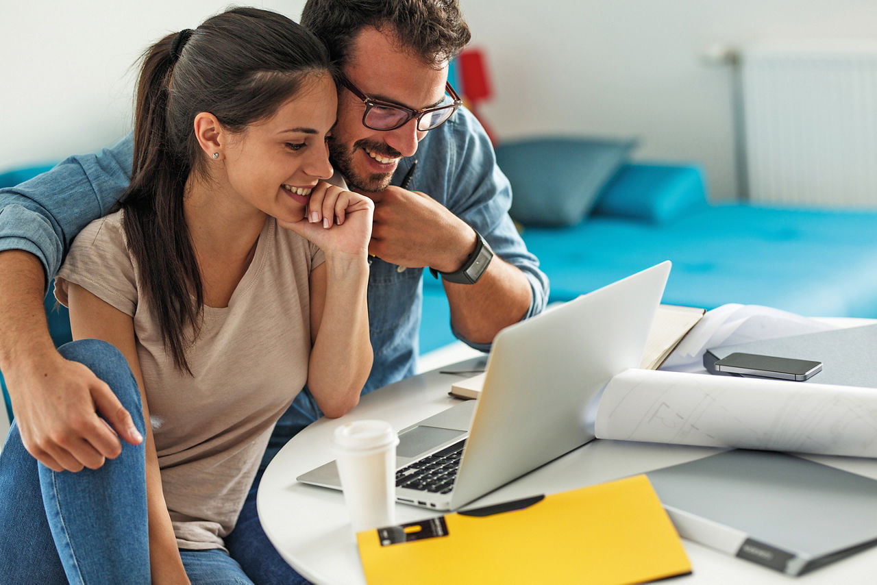 Junges Paar bei Online-Recherche zur Immobilienbewertung vor einem Laptop