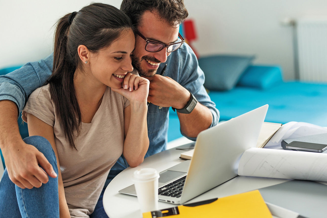 Junges Paar bei Online-Recherche zur Immobilienbewertung vor einem Laptop