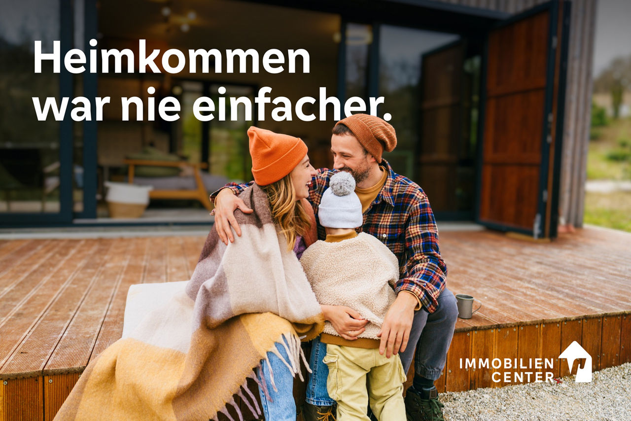 Junge Familie mit einem Kind sitzen auf der Terasse vor ihrem Haus