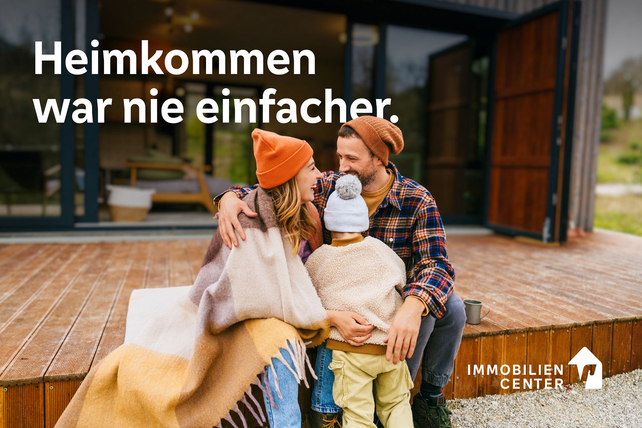 Junge Familie mit einem Kind sitzen auf der Terasse vor ihrem Haus