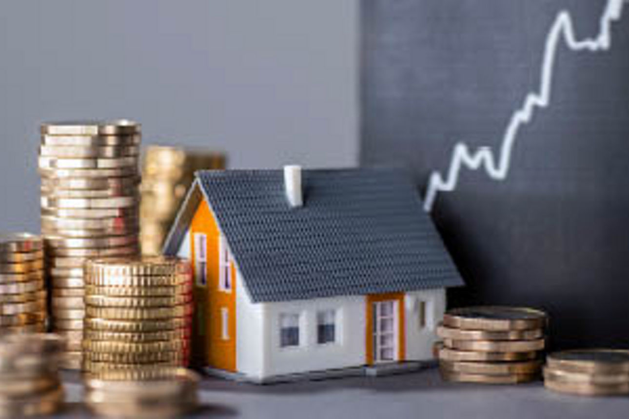 Ein Modellhaus mit Geldmünzen auf einer Ablage